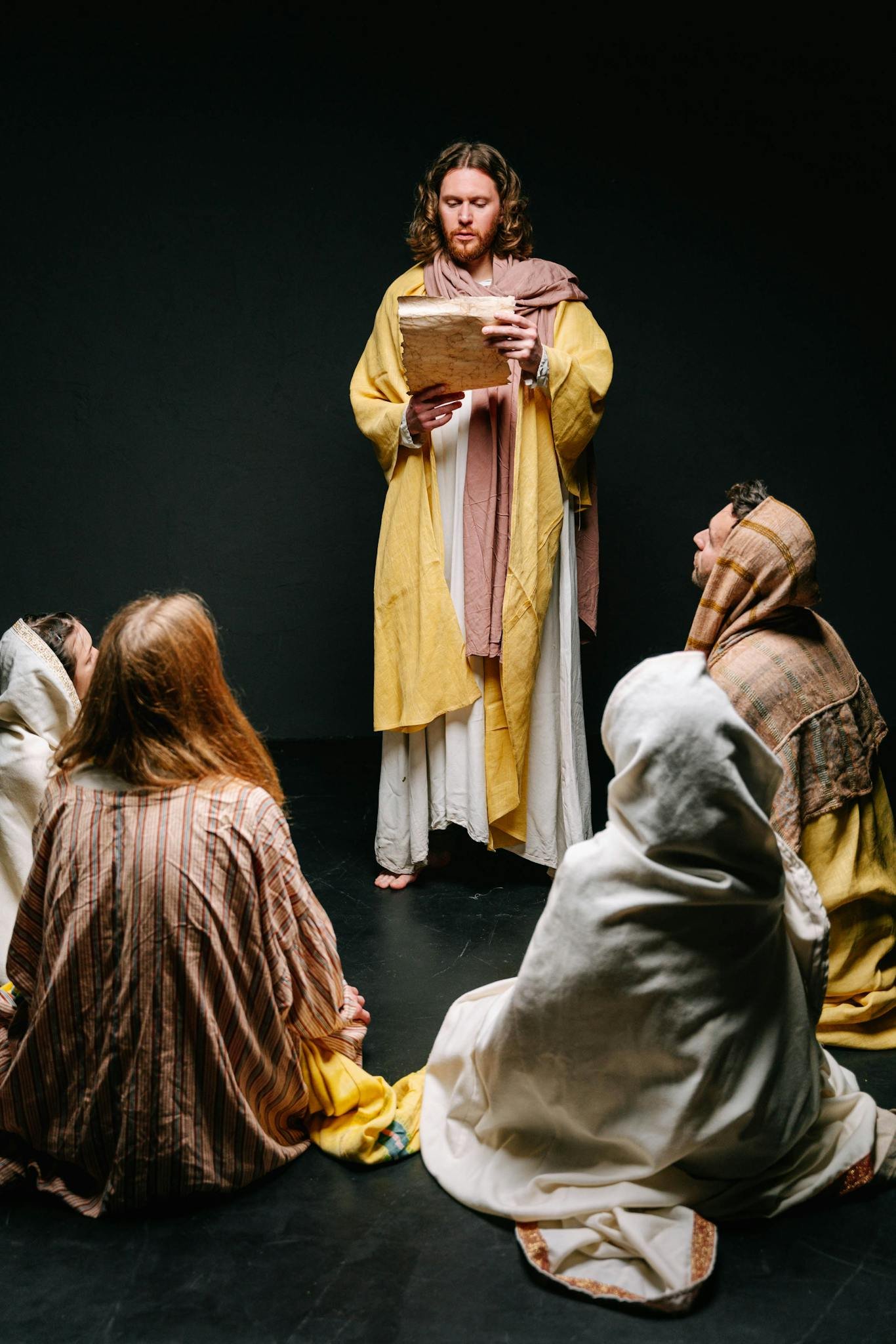 Jesus reading to a group of apostles in traditional attire, illustrating a biblical scene.